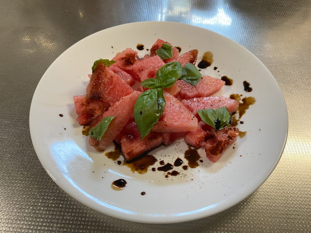 さらにスイカのカルパッチョが載っています。バジルが飾られて、塩・こしょう、バルサミコ酢がかかっています。