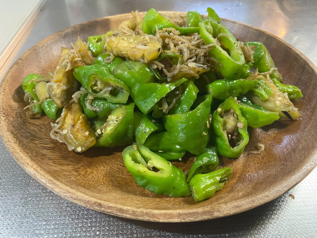 木の皿に小さくカットした万願寺、ナスとじゃこを炒めた料理が盛り付けられている