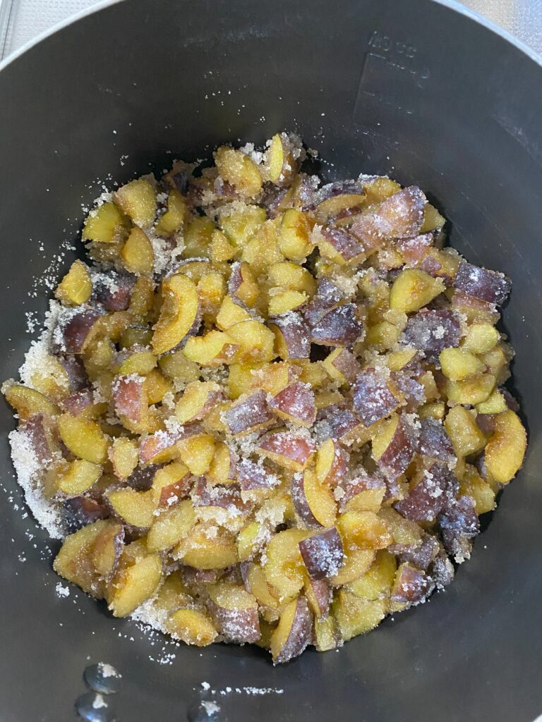 鍋の中にカットしたプルーンにフラニュー糖をまぶしている