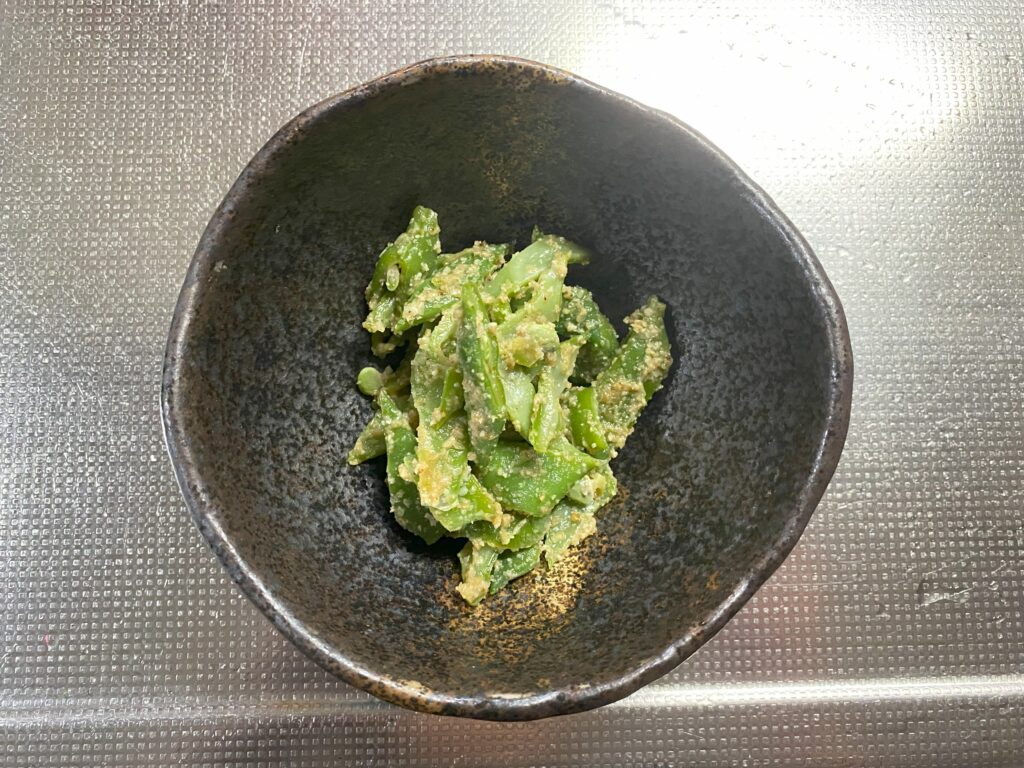黒い陶器の器にモロッコインゲンの胡麻和えが入っている。