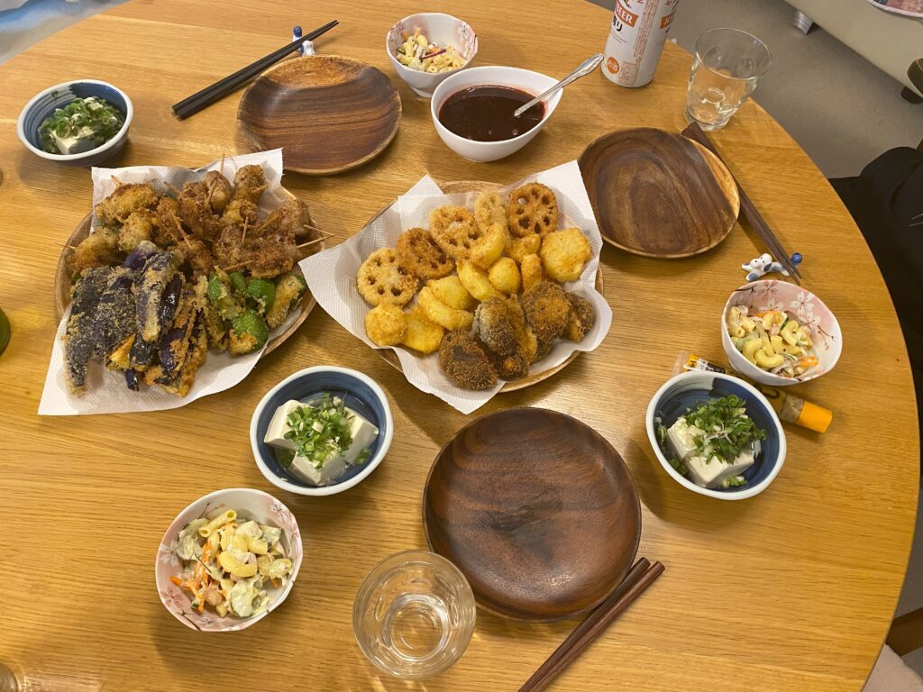 串カツ、ソース、副菜、ビールが食卓に並んだ様子