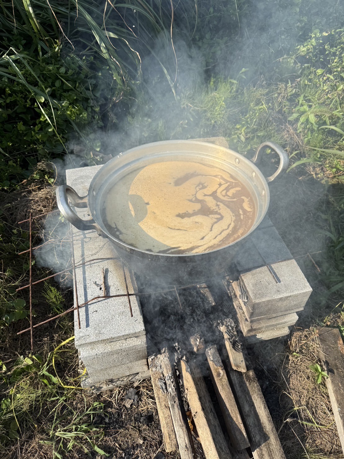 屋外の薪火でりんご果汁を煮詰める様子（手作りりんごシロップ）